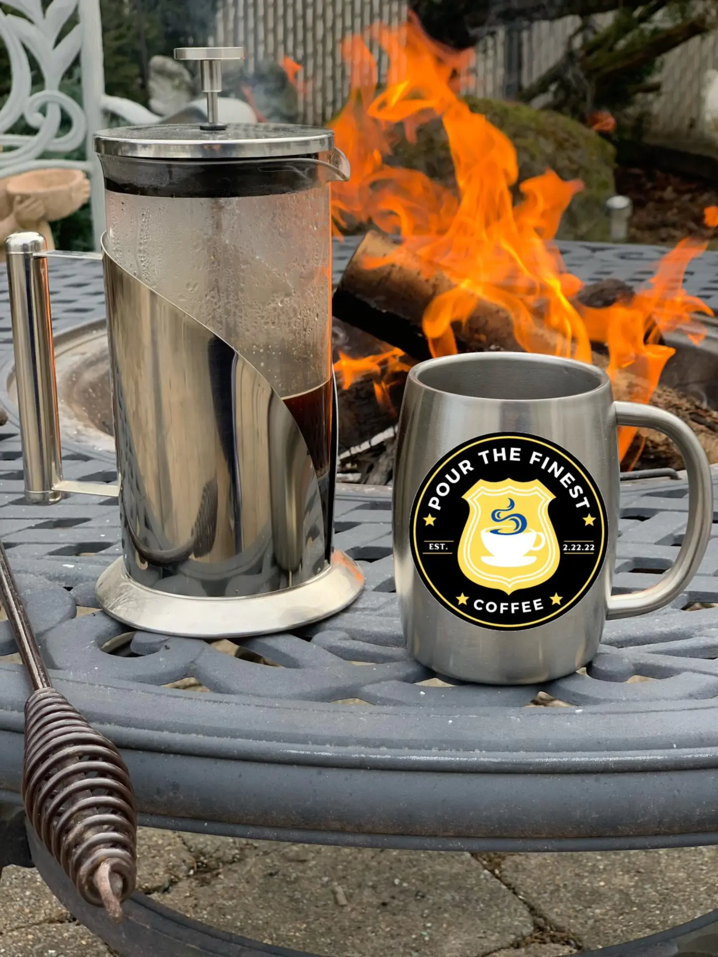 A round table with fire and coffee mug and cup are placed around