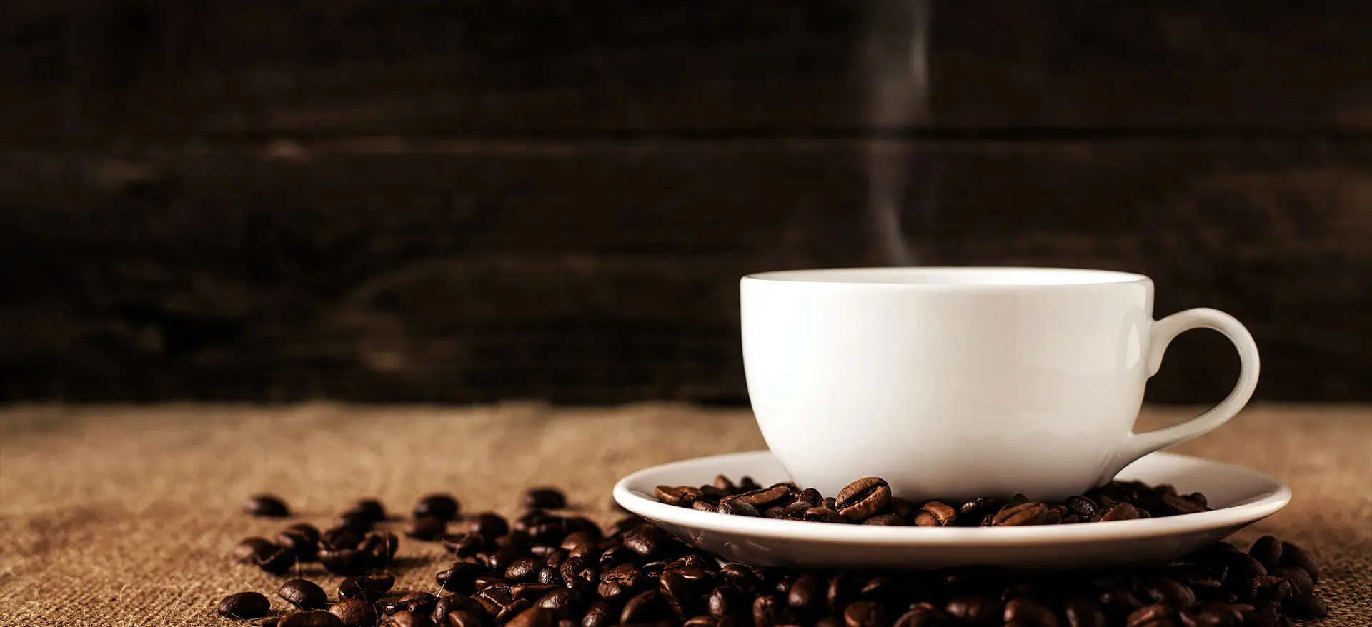 Still Life photography of steaming coffee beans in a white cup.